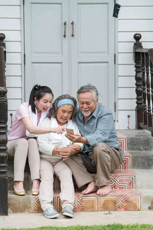 Asian young woman teach how to used mobile for online shoping older father and mother in outdoor...