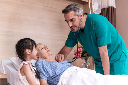 Male doctor check sickness of senior patient on patient bed, beside Lovely girl visit and encourage grandmother in hospital, healthcare and medical concept.の写真素材