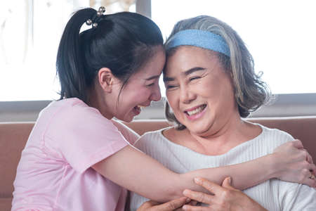 Asian young woman take care and warn hug mother, she is very happy and smile in living room.の写真素材