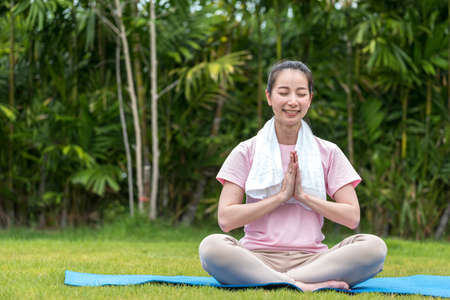 Asian Beauty and healthy woman exercise and doing meditation of yoga on exercise mat in the outdoor park -  fitness, sport, yoga concept.の写真素材