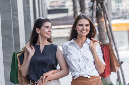 Young shopaholic friends women friends walking and carry shopping bags in the street city with happy and smiling.の写真素材