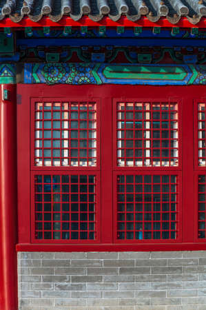 Red wooden window with decoration colorful painting beam and wood pole from ancient china palace in forbidden City, Beijing, Chinaの写真素材