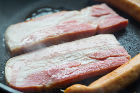 fried pork and sausage cooking in the pan close upの写真素材