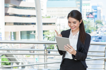 Happy young business woman with laptop working outdoor with urban background .  の写真素材