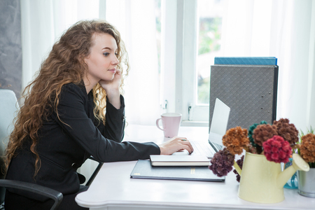 Young beautiful businesswoman sitting at desk working with laptop in officeの写真素材