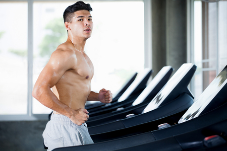 Muscular bodybuilder runner guy Exercise running on treadmill in the gym .sport young fitness man shirtless is working out training with running Exercise Machineの写真素材