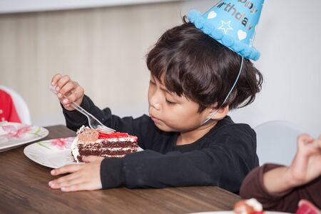 Little boy with hat eating birthday cakeの写真素材