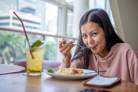 Happy smiling asian woman eating Italian pasta with lemonade in restaurants . 