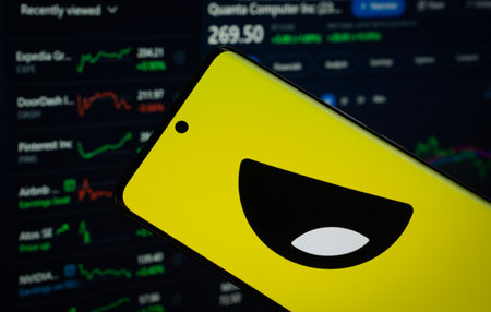 Dhaka, Bangladesh- 18 March 2025: Yubo logo is displayed on a smartphone screen, with a stock graph webpage visible on a computer screen in the background.のeditorial素材