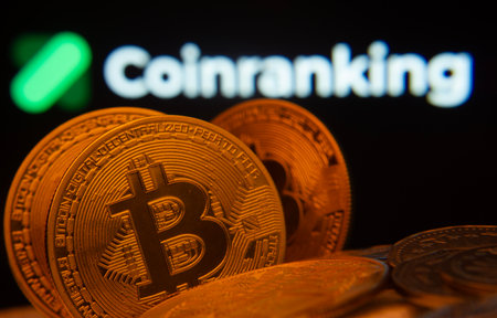 Dhaka, Bangladesh- 19 Sep 2025: Close-up of Bitcoin coins with the Coinranking logo visible on a screen in the background.のeditorial素材
