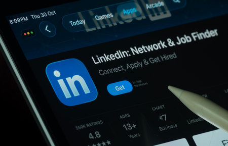 Dhaka, Bangladesh- 30 Oct 2025: LinkedIn app displayed on a iPad screen in dark mode with a digital pen pointing at it.のeditorial素材