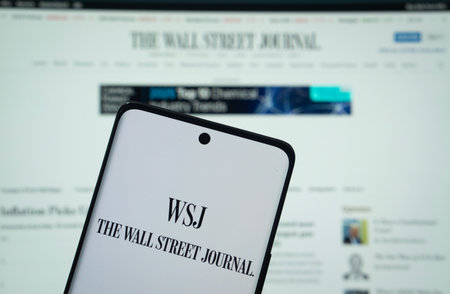 Dhaka, Bangladesh - 18 March 2025: The logo of the wall street journal is displayed on a smartphone screen, and the website is visible on a computer screen in the background.のeditorial素材