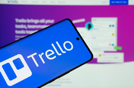 Dhaka, Bangladesh - 18 March 2025: The logo of the trello is displayed on a smartphone screen, and the website trello is visible on a computer screen in the background.のeditorial素材