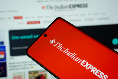 Dhaka, Bangladesh - 18 March 2025: The logo of The Indian Express is displayed on a smartphone screen, and the website is visible on a computer screen in the background.のeditorial素材