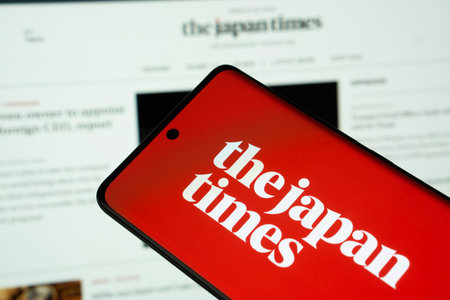 Dhaka, Bangladesh - 18 March 2025: The logo of the japan times is displayed on a smartphone screen, and the website is visible on a computer screen in the background.のeditorial素材