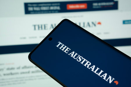 Dhaka, Bangladesh - 18 March 2025: The logo of The Australian is displayed on a smartphone screen, and the website is visible on a computer screen in the background.のeditorial素材