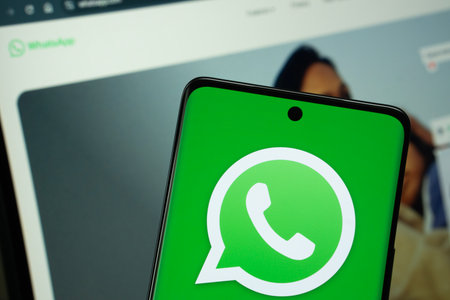 Dhaka, Bangladesh - 04 July 2025: The logo of the WhatsApp is displayed on a smartphone screen, and the website is visible on a computer screen in the background.のeditorial素材