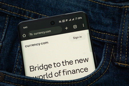 Dhaka, Bangladesh- 15 June 2025: A smartphone displaying the Currency.com web interface peeks out of...