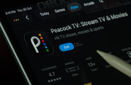 Dhaka, Bangladesh- 30 Oct 2025: Peacock TV app displayed on a iPad screen in dark mode with a digital pen pointing at it.のeditorial素材