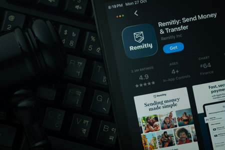 Dhaka, Bangladesh- 28 Oct 2025: An iPad displaying the Remitly app against a judge's gavel and dark keyboard background.のeditorial素材