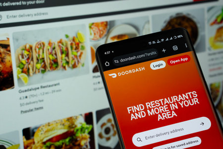 Dhaka, Bangladesh - 16 March 2025: The app of the DoorDash is displayed on a smartphone screen, and the website is visible on a computer screen in the background.のeditorial素材