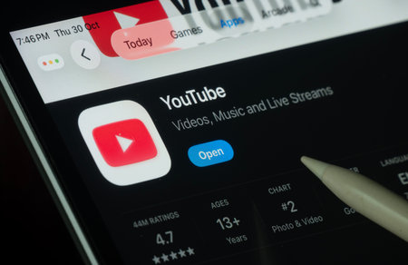 Dhaka, Bangladesh- 30 Oct 2025: Youtube app displayed on a iPad screen in dark mode with a digital pen pointing at it.のeditorial素材