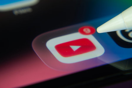 16 Nov 2025- Dhaka, Bangladesh: Stylus touching the youtube app icon with a notification on a smartphone screenのeditorial素材