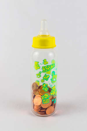 A shot of a baby milk bottle containing spare change - savings for the child's future.の写真素材