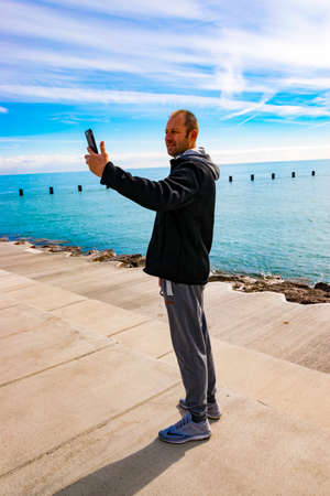 Chicago, IL, United States - March 12, 2017: A man is taking a self-portrait (selfie) picture in Chicago, Illinois by Lake Michigan.のeditorial素材