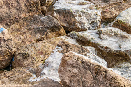 A shot of rocks in water and some ice covering a prt of them.