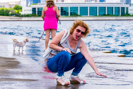 Chicago, IL, United States: June 18, 2017 - Woman is freaked by the the low temperature of water in Lake Michigan in Chicago, Illinois.のeditorial素材