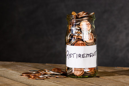 Retirement savings in a lgass jar on a dark background.