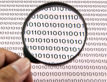 Hand holding magnifying glass. Examining binary code using magnifying glass.の写真素材