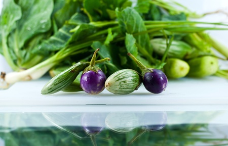 Preparation fresh vegetables on white plastic kitchen cutting board reflection on glass.の写真素材