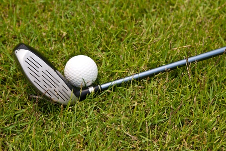 Golf ball and golf club sitting in green grass の写真素材