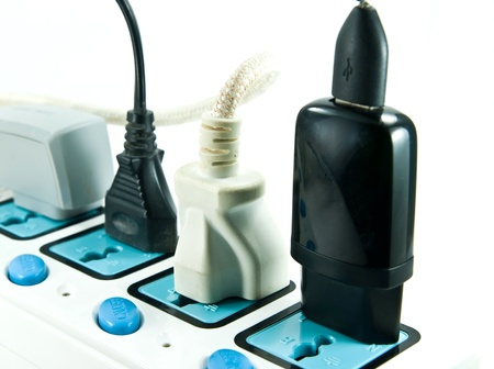 Many plugs plugged into electric power bar 
