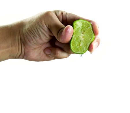 Hand squeezing juice from a green lime. Isolated on white background.の写真素材