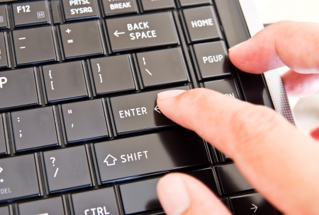 Hand touching laptop computer keyboardの写真素材