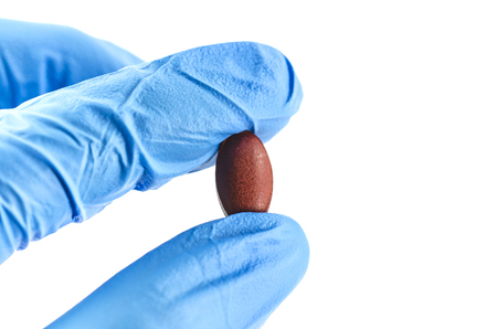 Hand in medical gloves holding one pillの写真素材