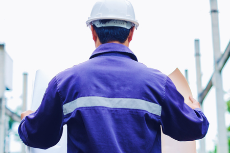 Engineer with white safety helmet holding project plan at construction outdoor site background, industrial conceptの写真素材