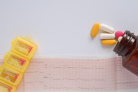 Medicine pills, vitamins, bottle and box on Cardiogram and white background with copy space, Healthcare and medical conceptの写真素材