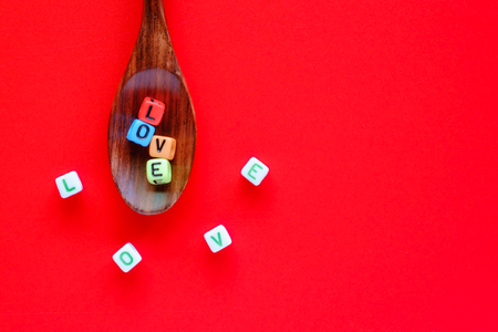 LOVE word from alphabet letter bead on wooden spoon and spreading out on red background with copy space for Valentine's day and taste of love conceptの写真素材