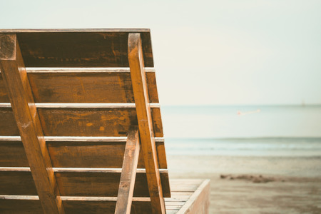 Close up of wooden chair backrest on the sandy beach for summer vacations concept, added colour filter and vintage styleの写真素材