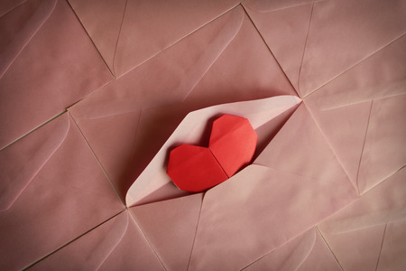 Red heart paper origami in pink envelope background for Valentine's day concept, added colour filter...