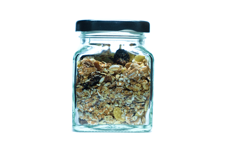 Granola or muesli - a mixture of cereals, dried fruit, and nuts in glass jar on white background for healthy eating and breakfast conceptの写真素材