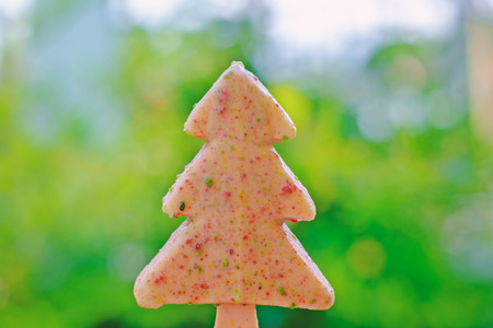Christmas tree white chocolate ice-cream on blurred natural green background for summer sweet eating conceptの写真素材
