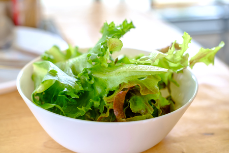 Fresh vegetable salad in the white bowl on the wooden table for for diet and healthy eating conceptの写真素材