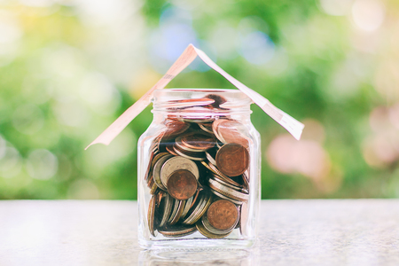 Banknote roof cover the glass jar of coins against blurred natural green background for property, investmant, business and finance conceptの写真素材
