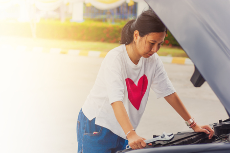 Asian young woman holding a wrench for fixing a broken car for transportation and vehicle conceptの写真素材