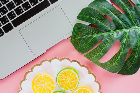 Computer laptop with green leaf palm and lemon slice on pink color background for food planning concept. Flat lay and top view image.の写真素材